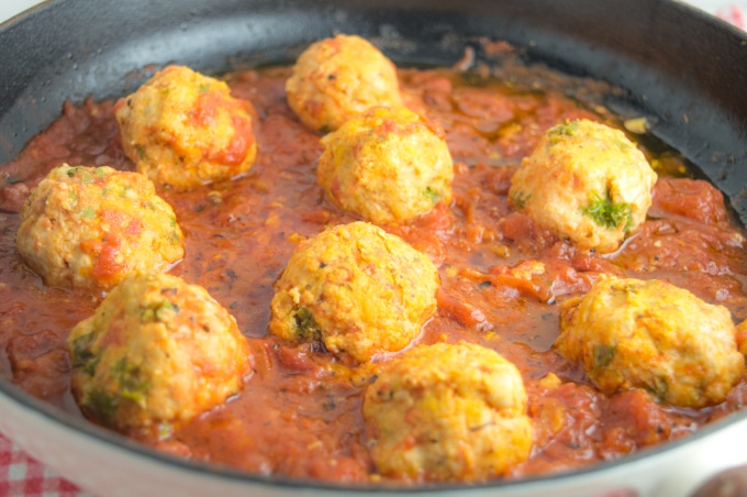 turkey meatballs cooking in tomato sauce, inside an iron casted skillet