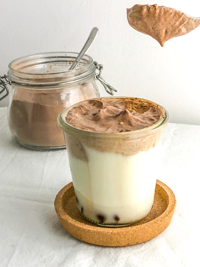 a glass of milk topped with and with a spoon of whipped chocolate
