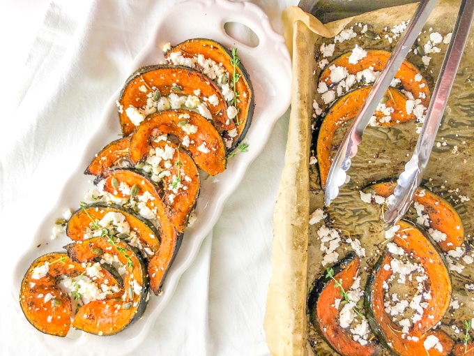 A plate and a tray filled with roast pumpkin wedges topped with feta and thyme