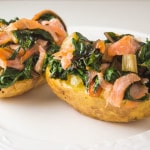 two potato halves loaded with smoked salmon and swiss chard