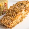 zoomed image of a salmon fillet with sesame seeds, with quinoa side on the background