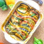 A small oven dish with a colorful summer vegetable gratin, topped with cheese