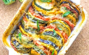 A small oven dish with a colorful summer vegetable gratin, topped with cheese