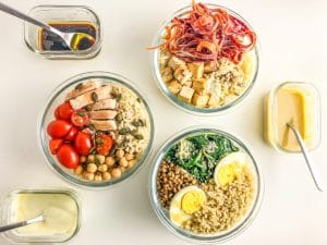 three packed nourish bowls with three dressings in a rectangular container