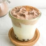 A glass of milk topped with whipped chocolate and sprinkled with cinnamon