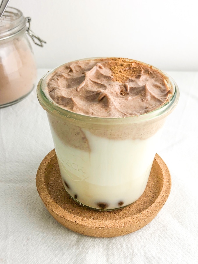 A glass of milk topped with whipped chocolate and sprinkled with cinnamon