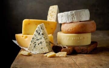 diferentes tipos de queijo empilhados em cima de uma tábua