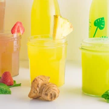 three glasses with pink, yellow and green agua fresca and decorated with fruits and leaves