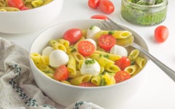 bowl filled with caprese pasta salad with pesto