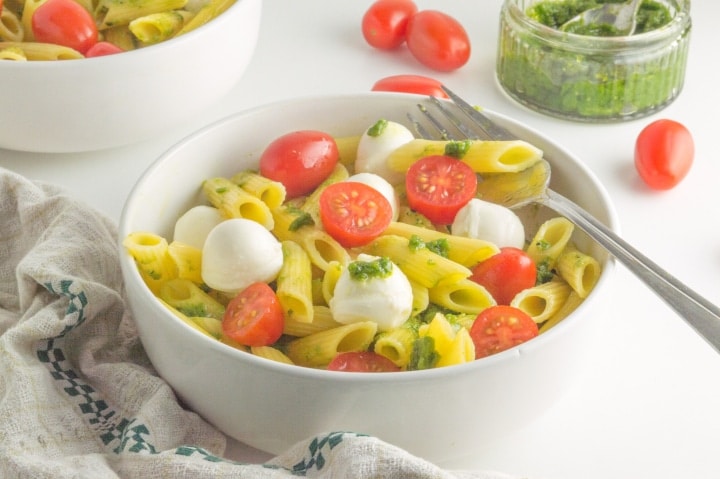 bowl filled with caprese pasta salad with pesto