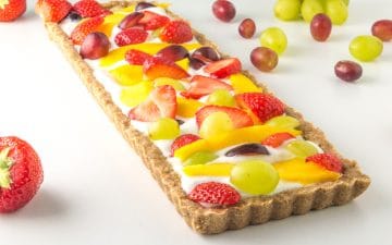 a low fodmap fruit tart surrounded by fresh fruit